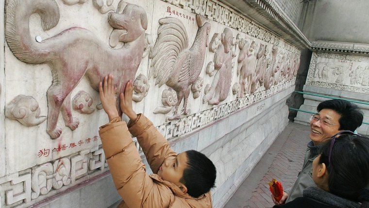 بكين ، الصين: طفل يفرك يديه من أجل حظ سعيد على منحوتة من الكلب على طول جدار يصور الاثني عشر حيوانًا من التقويم القمري ، 27 يناير 2006 ، في معبد السحابة البيضاء (Baiyun Guan) في بكين. تأسست معبد White Cloud الذي تأسس في A.D 739 ، وهو واحد من أقدم المعابد الطاوية في شمال الصين ويجذب الآلاف من الزوار في معرض المعبد خلال عطلات الربيع للاحتفال بالعام القمري الجديد ، الذي يقع في 29 يناير مع عام The Year of the كلب. AFP Photo/Frederic J. Brown (يجب أن يقرأ رصيد الصورة فريدريك ج.